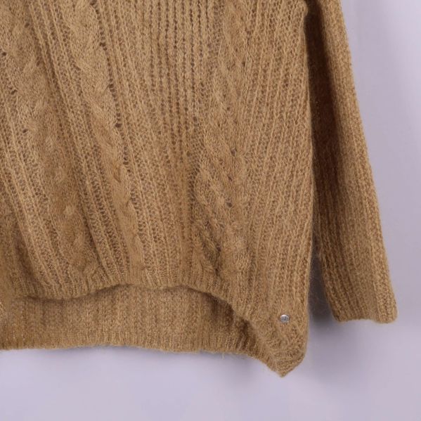 Hörndetalj av stickad tröja med metallbricka