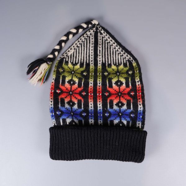 Stickad luva med tofs och färggranna mönster framifrån