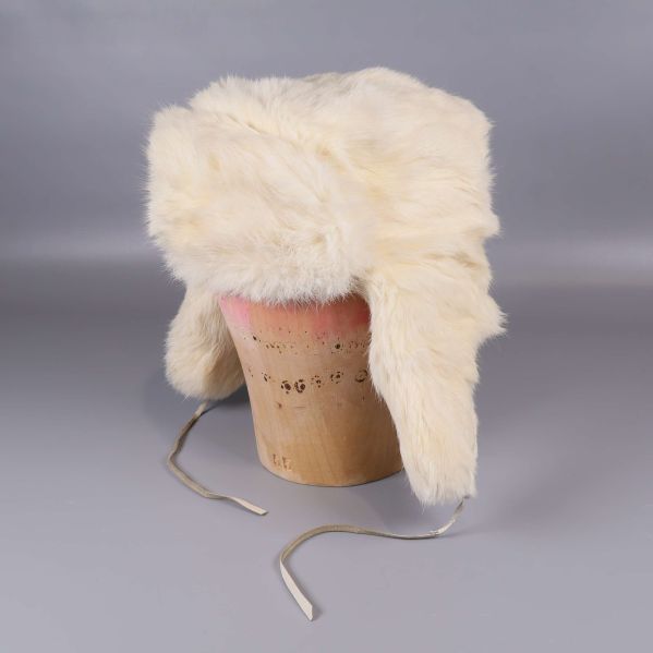 Vit trappermössa i fuskpäls på träställning