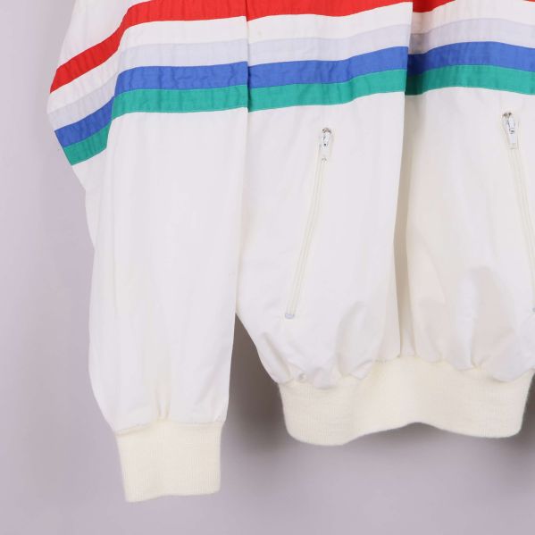 Nedre del av vit jacka med dragkedjefickor och färgade ränder