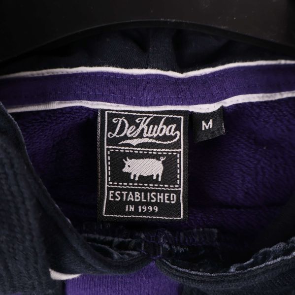 Närbild på DeKuba-märkesetikett och storlek M i nacken