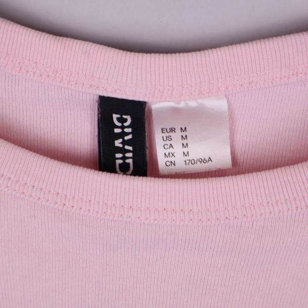 Storleksetikett på rosa crop top, visar storlek M