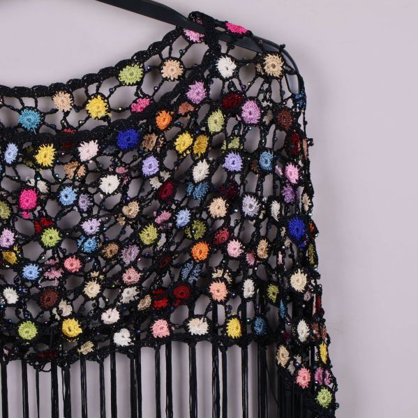 Närbild på virkad poncho med små virkade blommor i olika färger