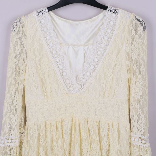 Närbild på spetsmönster och V-ringning med dekorband