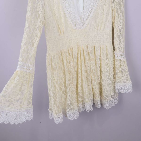 Klockärm och midjeparti på spetsblus syns från sidan