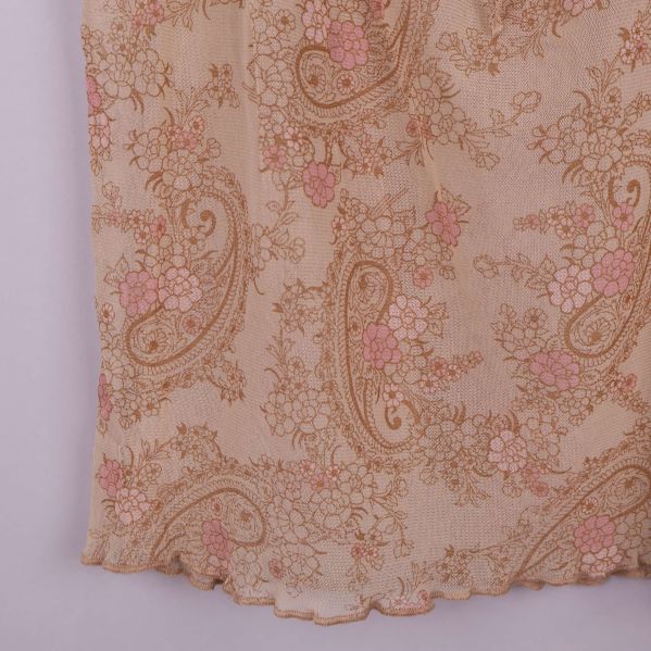 Närbild på blusens tyg med paisleymönster och mjuka färger