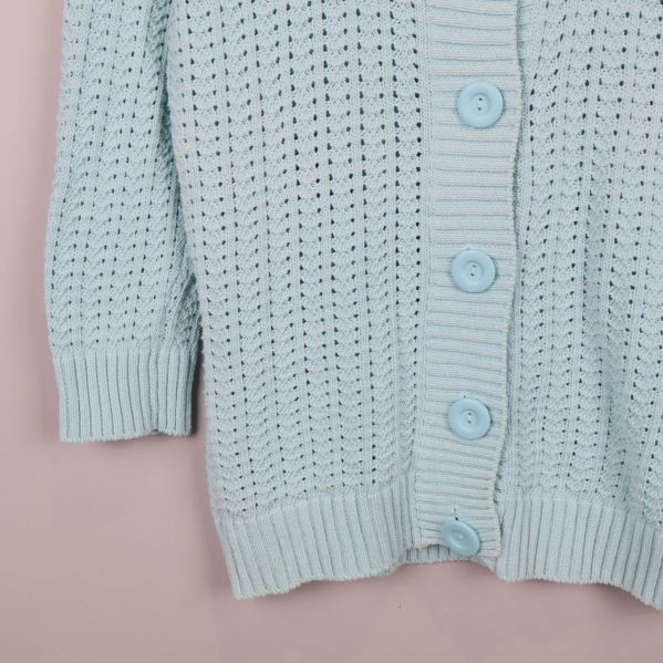 Nedre delen av ljusblå kofta med ribbade muddar och knappar