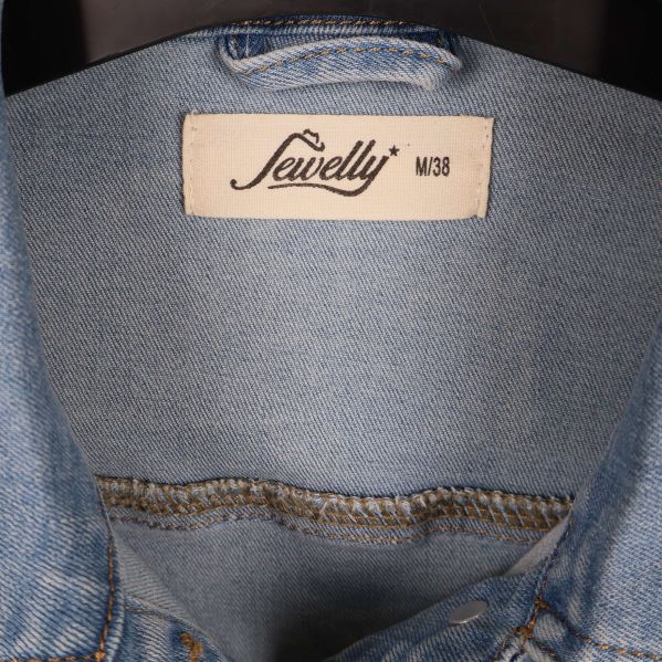 Närbild på Sewelly etikett och storlek M38 i jackan