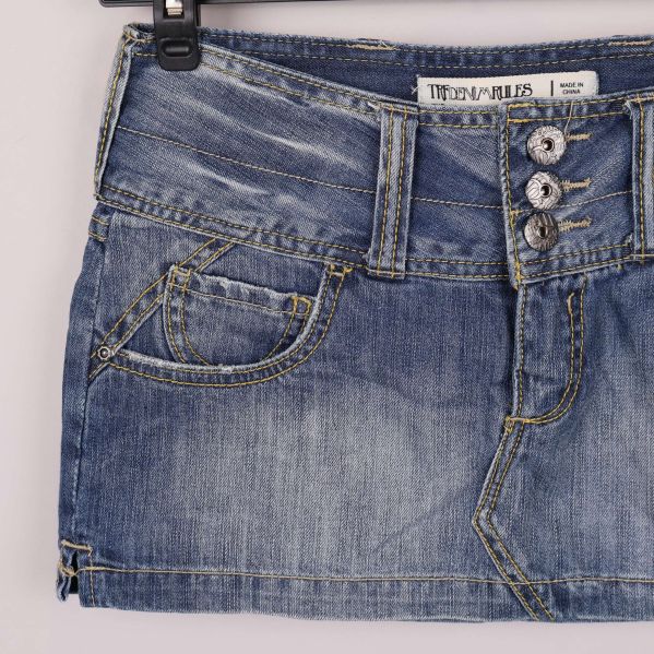 Närbild på vänster ficka och knappar på jeanskjol