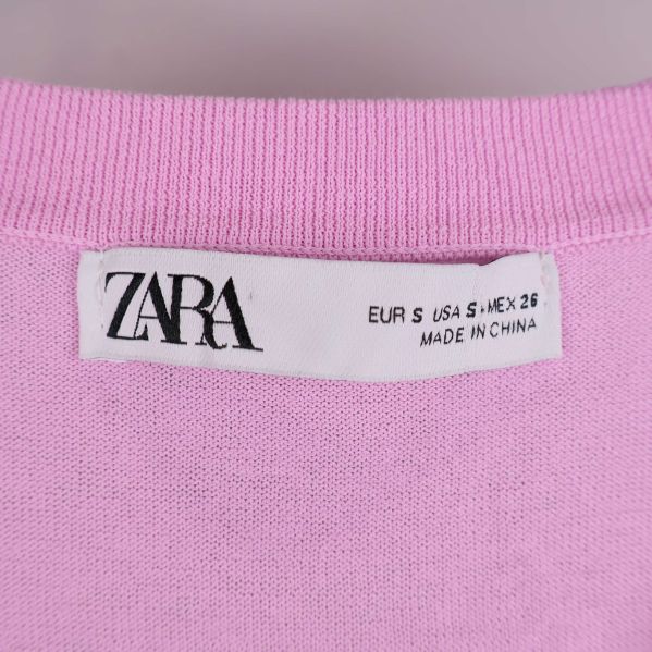 Närbild på ZARA-etikett i halsen på rosa tröjan