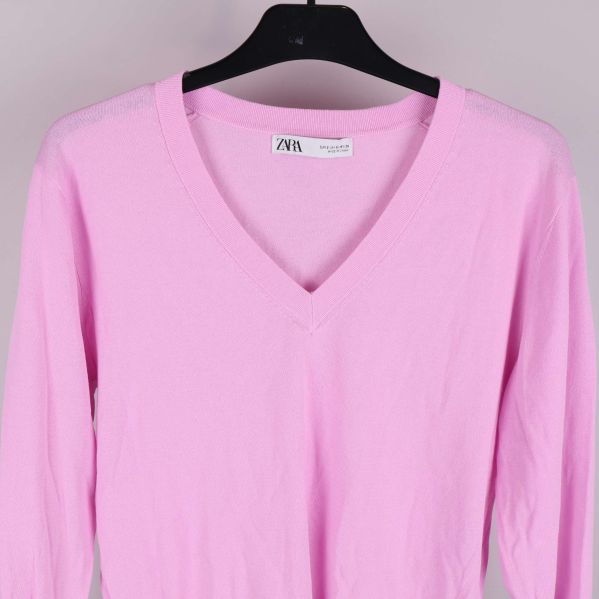 Detalj av v-ringningen på ljusrosa tröja