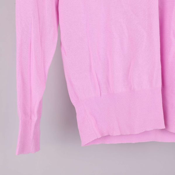 Närbild på ribbad nederkant och ärmslut av rosa tröja