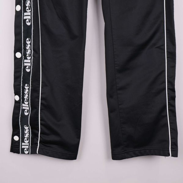 Detalj av byxbenets logoband och runda vita tryckknappar