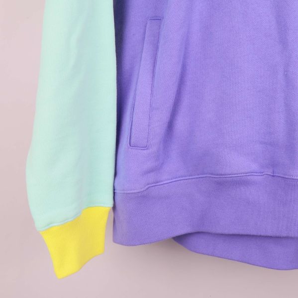 Närbild på ficka och ribbad nederkant i lila tyg