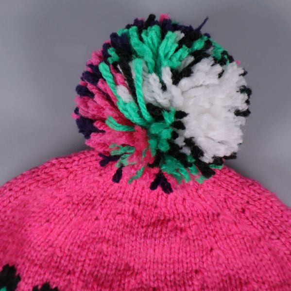 Närbild på tofs i grönt, vitt och svart