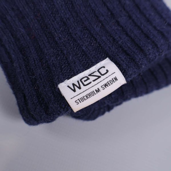 Närbild på WESC-logga på vante i blått tyg