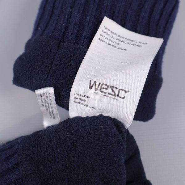Två vita tvättrådsetiketter med WESC-tryck visas i detalj