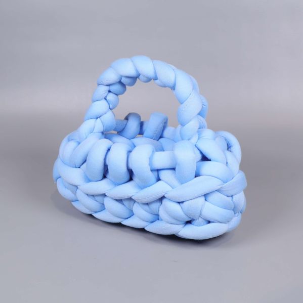 Stickad handväska i ljusblått med handtag syns från sidan