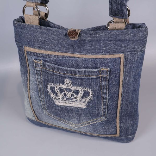Närbild på jeansväska med detaljsydd ficka och kronbroderi