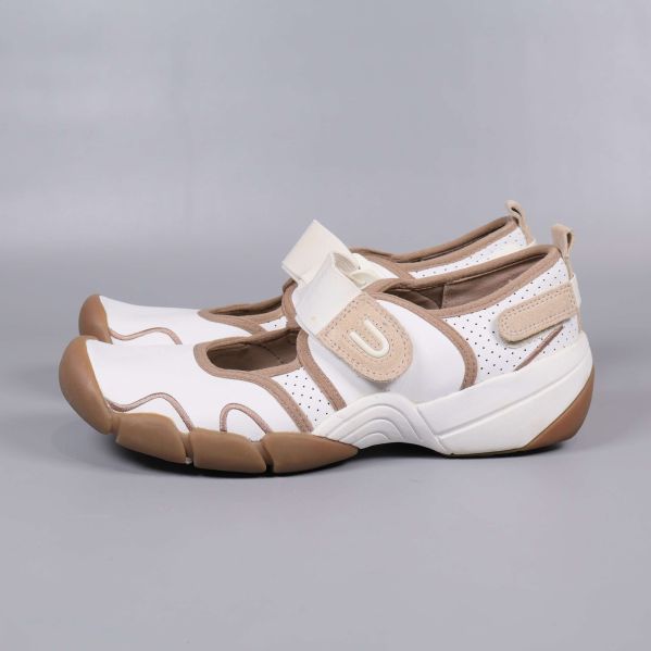 Sida av vit och beige sko med perforering och kraftig sula