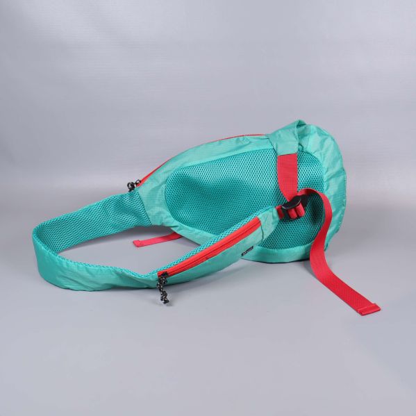 Turkos axelväska liggande med röda remmar och blixtlås