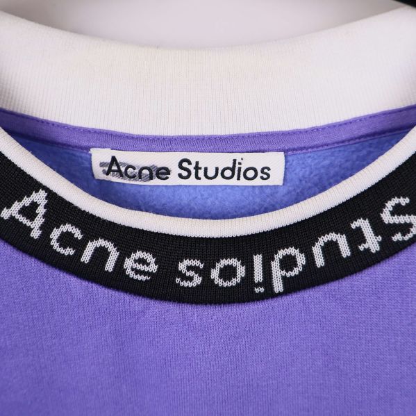 Närbild på logotypetikett Acne Studios i kragen