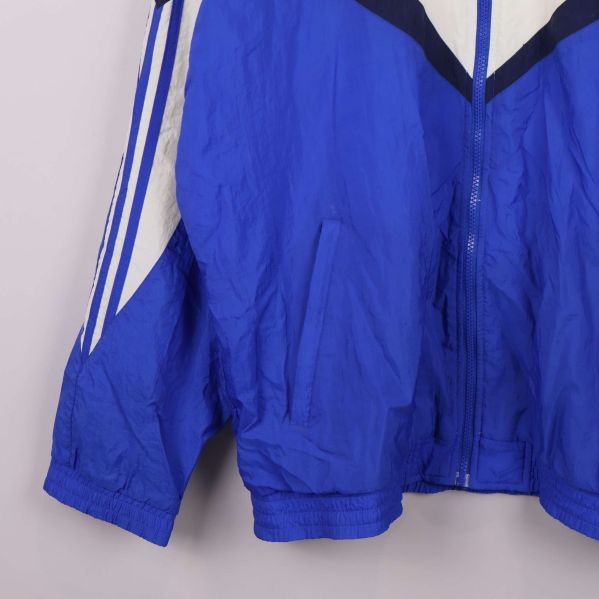 Närbild av nedre delen samt ficka på blåvit Adidas jacka