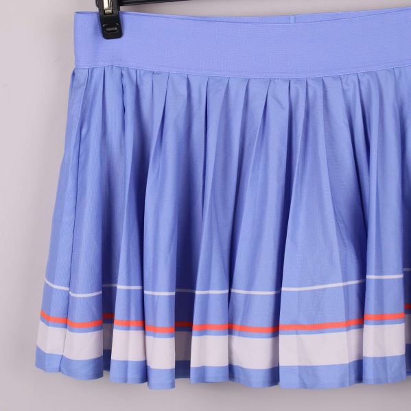 Närbild på plisserad kjol med vita och orangea ränder