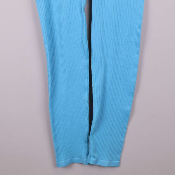 Ben och tygstruktur på blå ribbade leggings i närbild