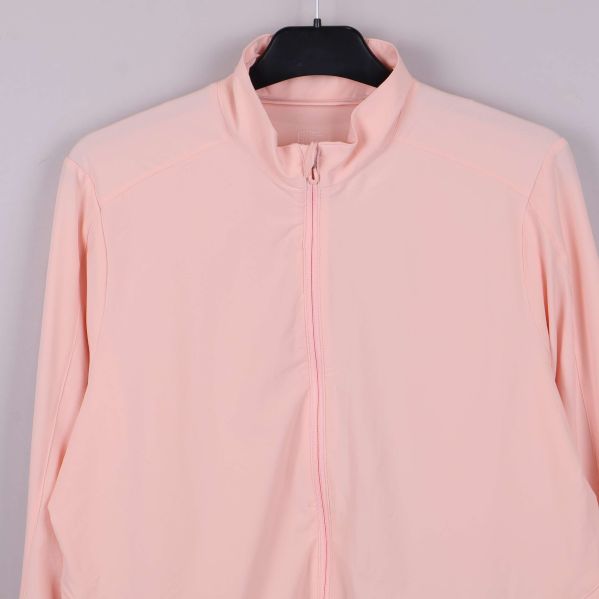 Närbild på jackans krage och dragkedja i ljus aprikos