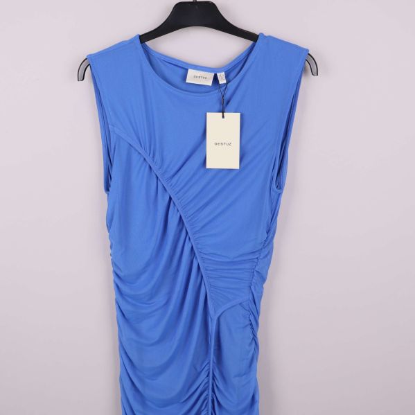 Närbild av överdelen på klarblå klänning med etikett