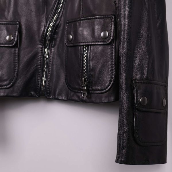 Detaljbild på svart läderjackas fickor och dragkedja