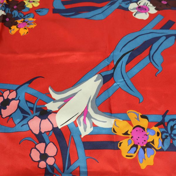 Närbild på scarf med färgglada blommor och blå detaljer