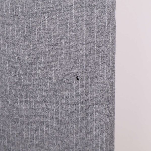 Närbild på litet hål på vänster lår av byxan