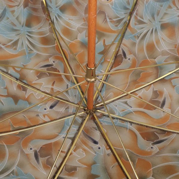 Insidan av paraplyet med mässingsfärgade ekrar och trästång
