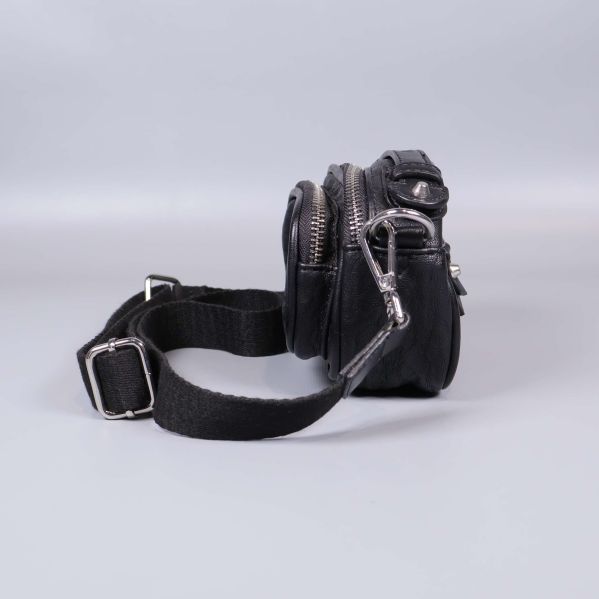 Svart väska sedd från sidan visar dragkedjor och fästen