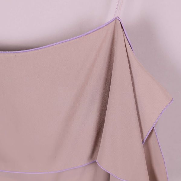 Närbild på axelband och volangkant med lila söm