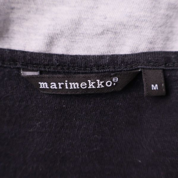 Närbild av Marimekko-loggan och storlekslapp i kragen