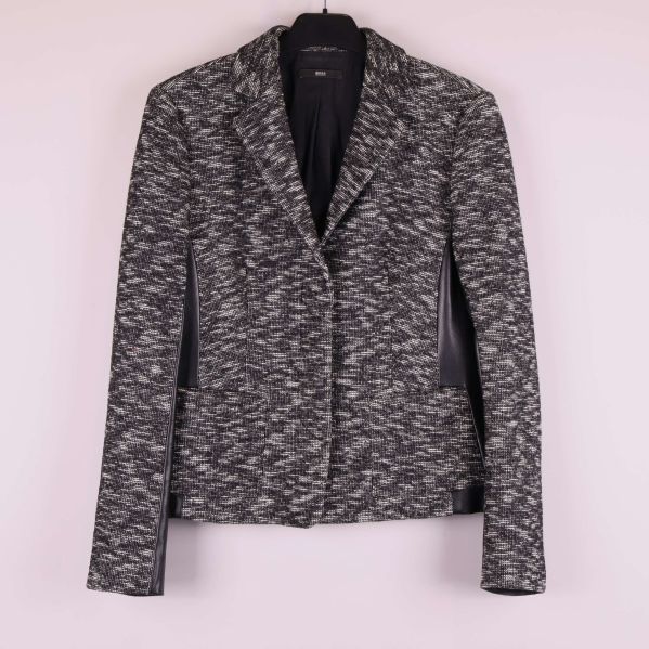 Kavaj i svart och grått mönster på galge mot ljus vägg