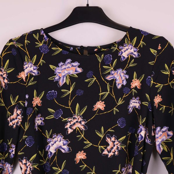 Närbild på halsringning och axlar med blommig design