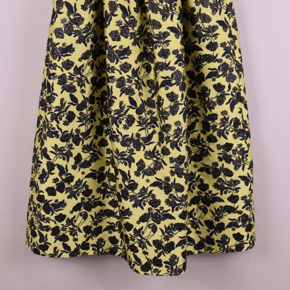 Blommigt tyg i marinblått på ljusgul bakgrund, närbild på kjolen