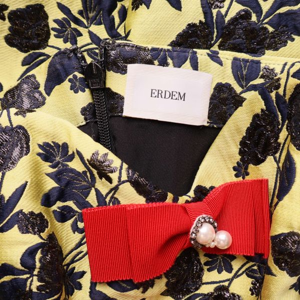 Närbild på Erdem-logga och röd rosett med pärlor