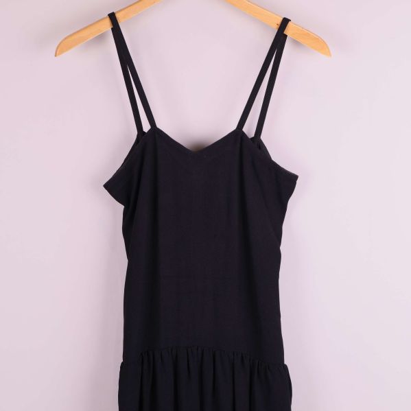 Detaljvy av överdelen med axelband på svart klänning