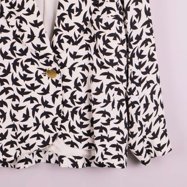 Närbild på kavajens fågelmönster och material