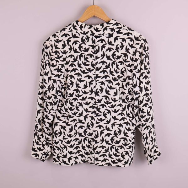 Kavaj med svart fågelmönster bakifrån på galge