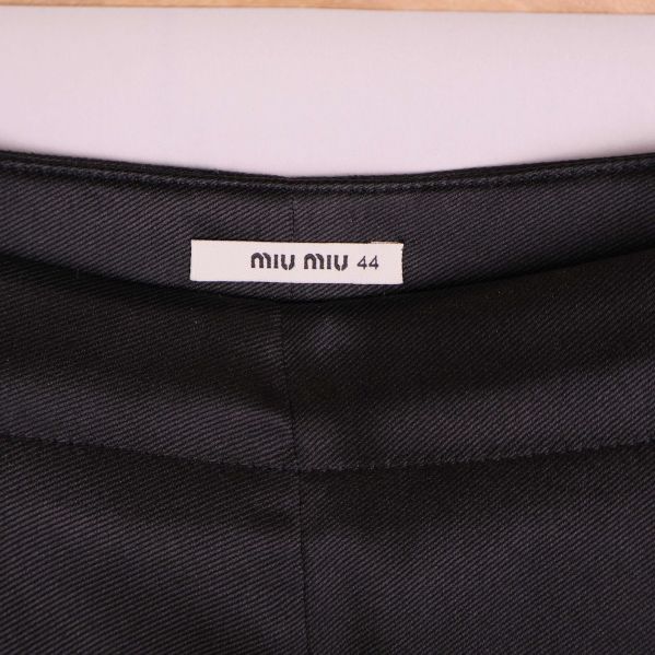 Närbild på Miu Miu-etikett i linningen på svarta byxor