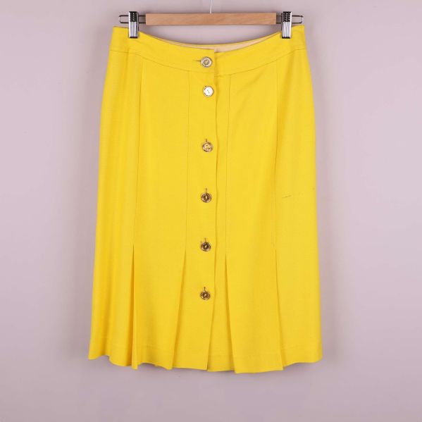 Kjol i starkt gult med knappar framtill på galge