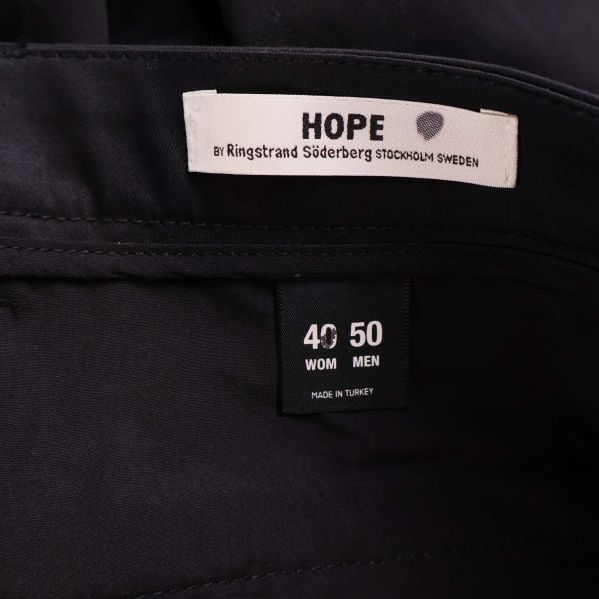 Närbild på etikett med storleksinfo för HOPE byxor