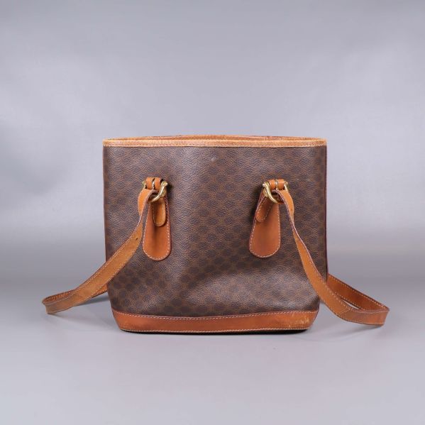 Baksida av brun toteväska med mönster och läderremmar