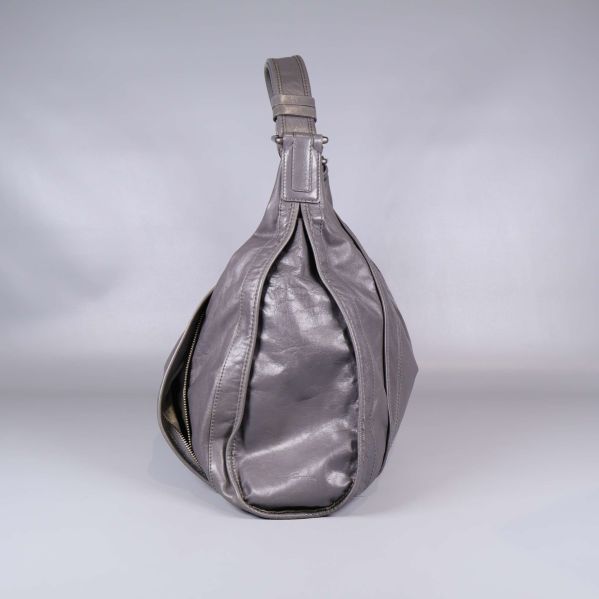 Väska i grått läder sedd från sidan med brett handtag